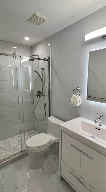 A bathroom with a toilet , sink , shower and mirror.