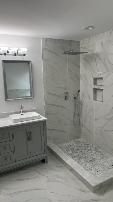 A bathroom with a sink , mirror , and walk in shower.