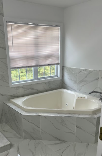 A bathroom with a jacuzzi tub and a window.