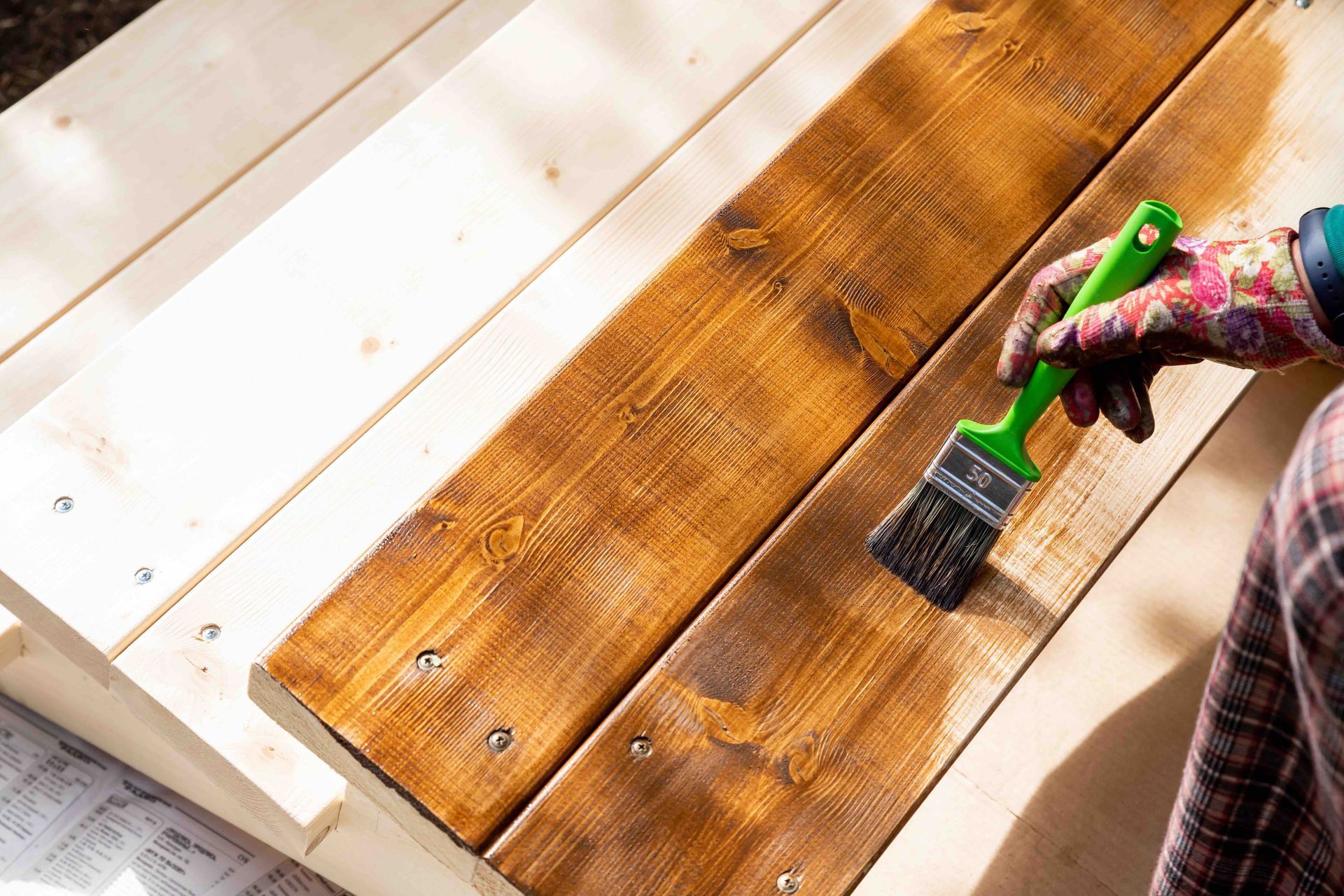 A person is painting a wooden bench with a brush.