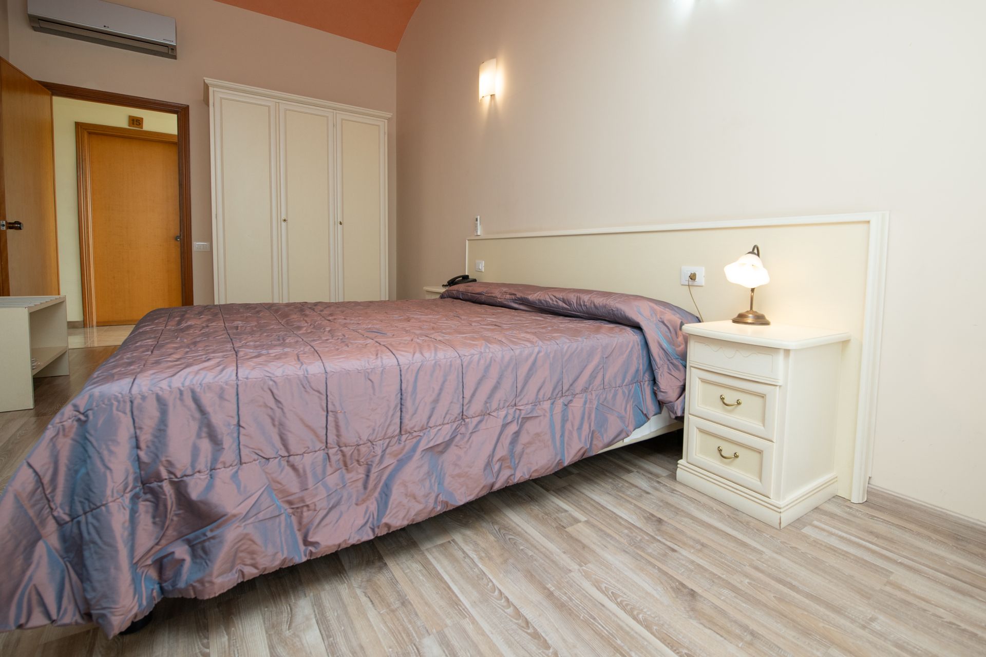 Una camera da letto con un letto, un comodino e una lampada.
