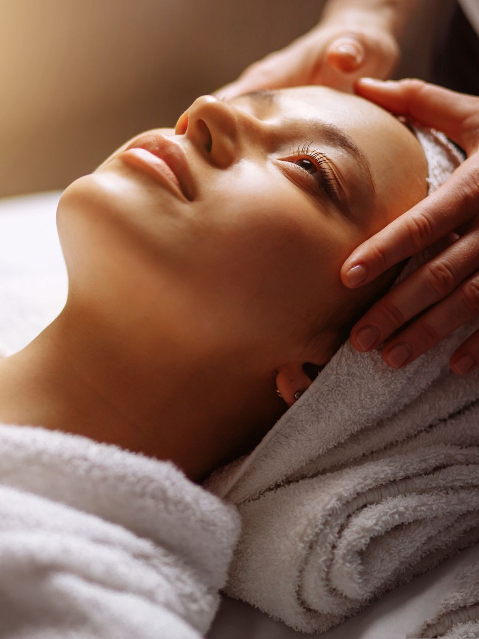 Woman with towel on head receiving facial treatment