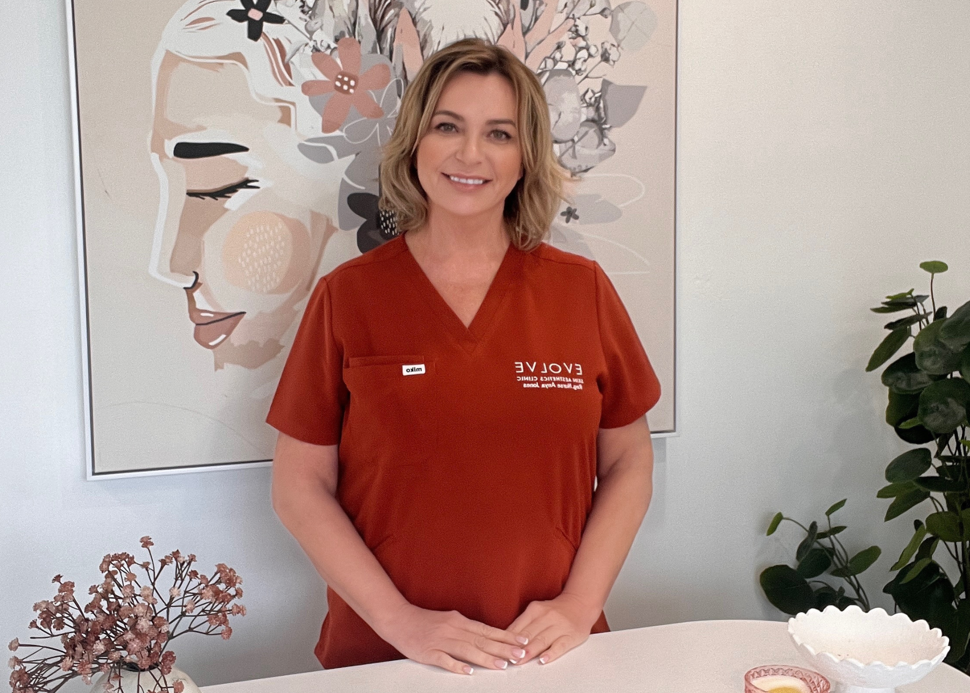 Woman smiling with brown hair flowing and hands on face