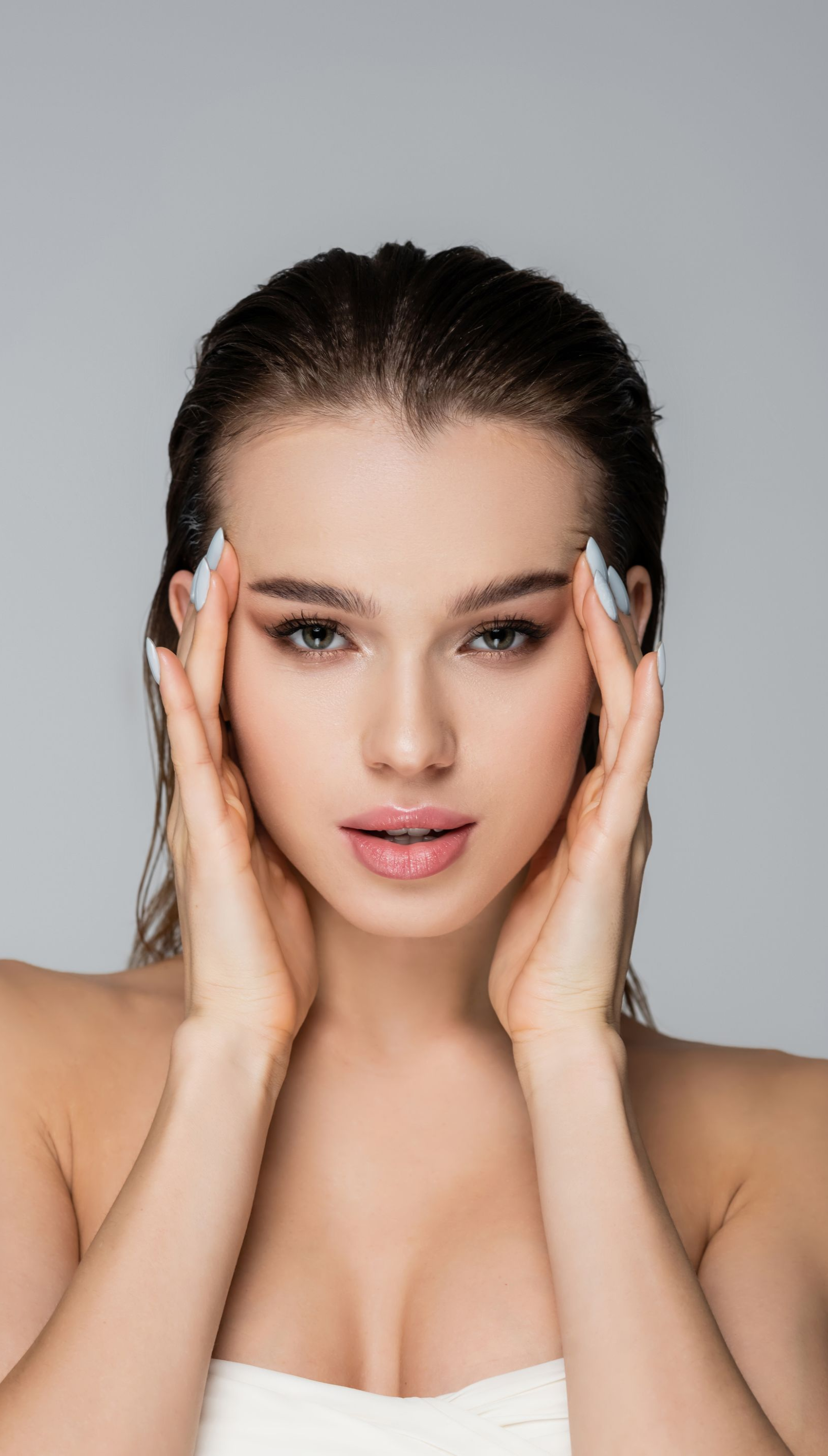 Woman holding hands on face with hair slicked back