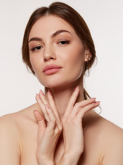 Woman holding hands up to face with pale pink nails