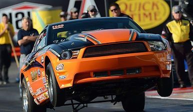 An orange and black race car is on a race track.