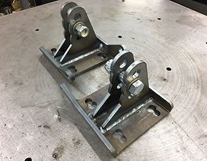 A pair of metal brackets sitting on top of a metal table.