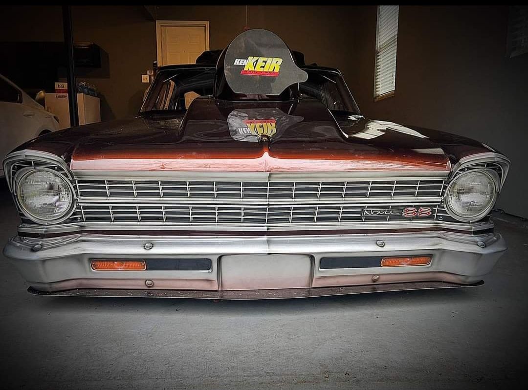 An old rusty car is parked in a garage.
