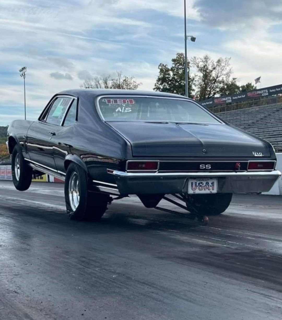An old rusty car is parked in a garage.