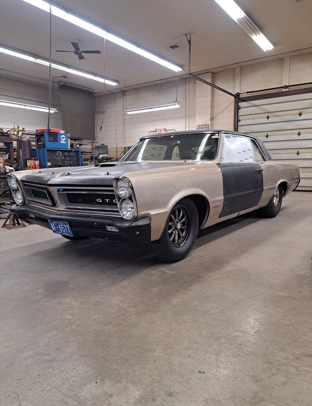 A car is parked in a garage next to a garage door.