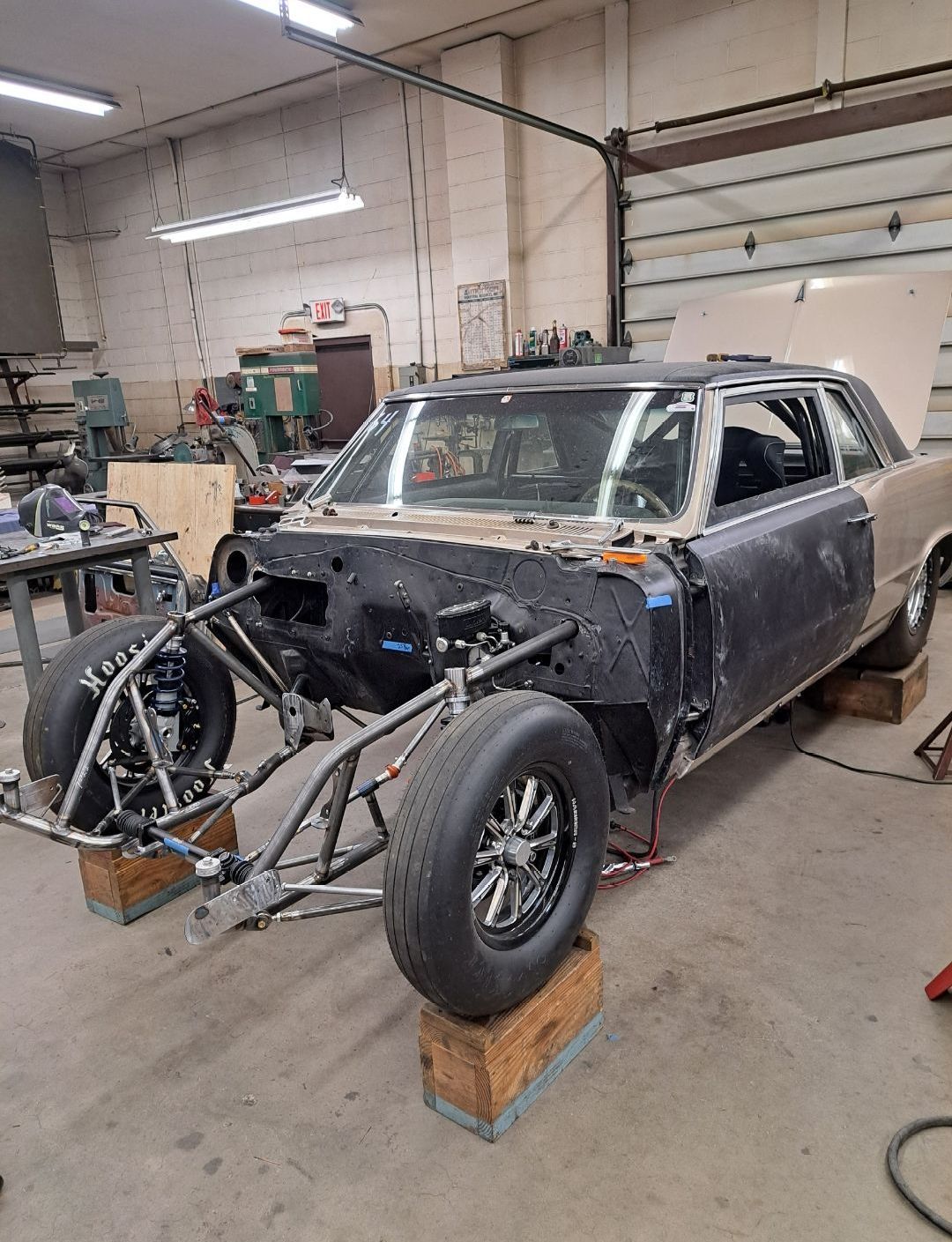 A car is being built in a garage with the hood up.