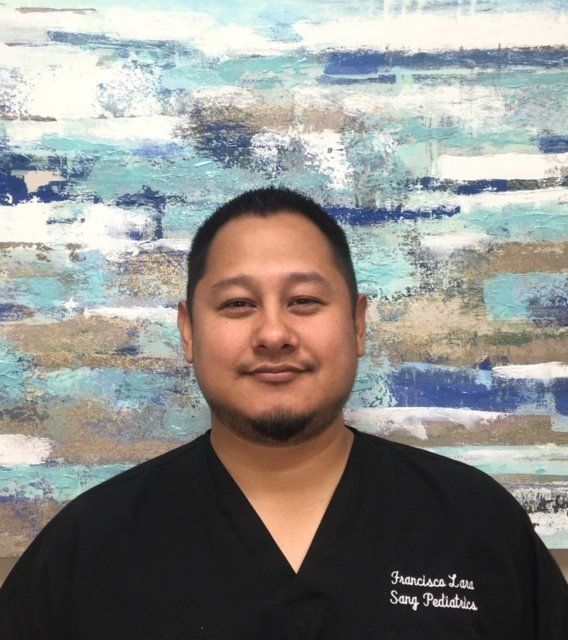 A man in a black scrub is standing in front of a painting.