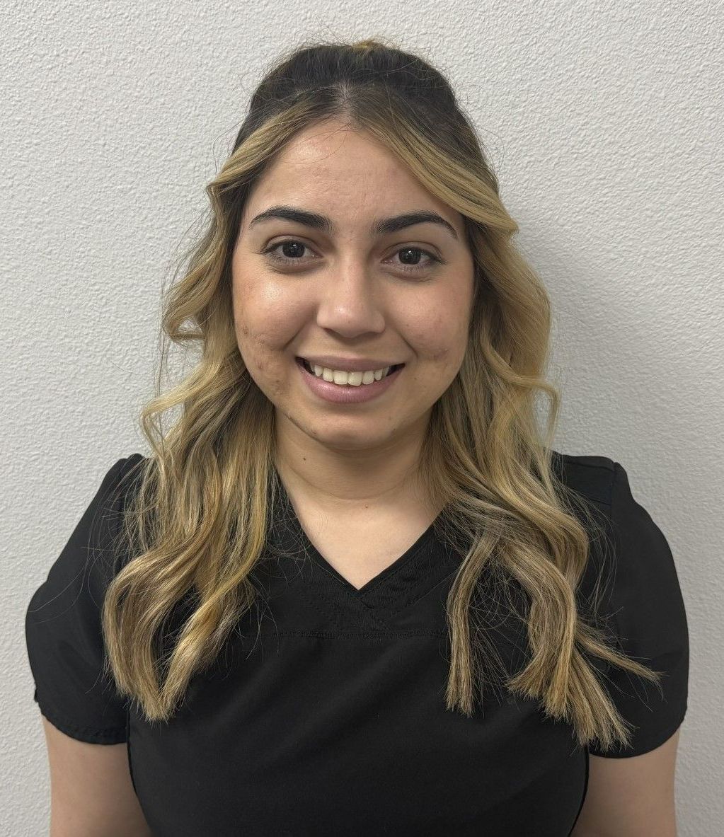 A woman in a black scrub top is smiling for the camera.