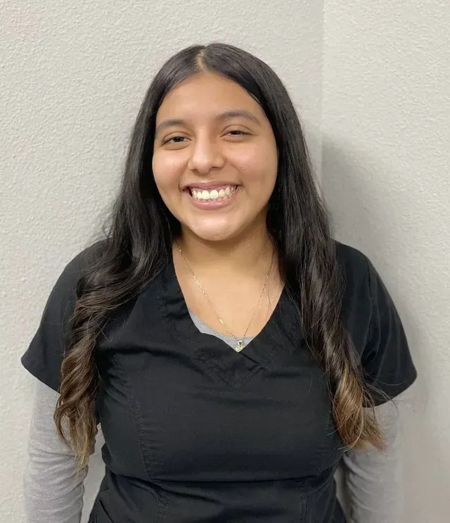 A woman in a black scrub top is smiling for the camera.