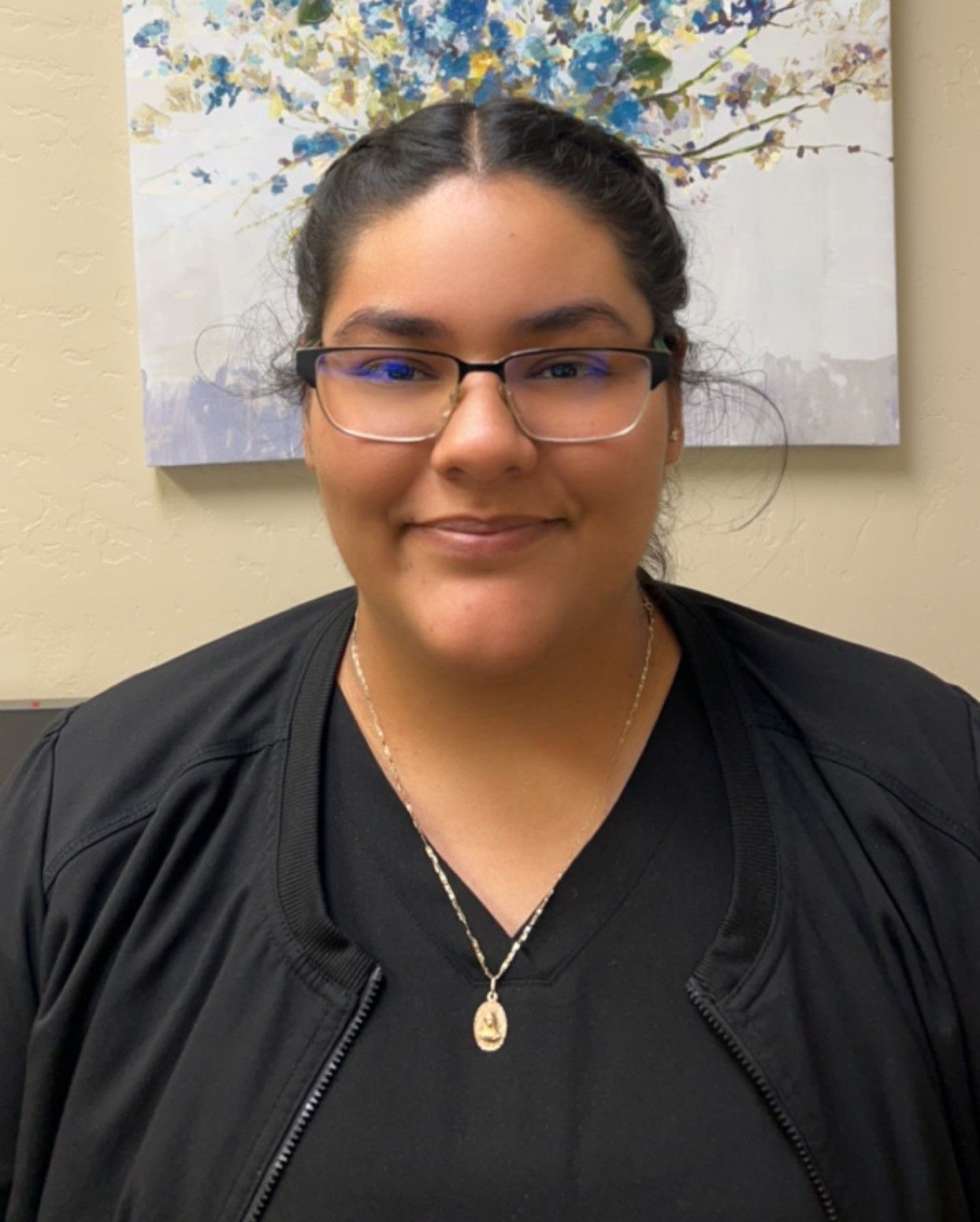 A woman wearing glasses and a necklace is smiling for the camera.