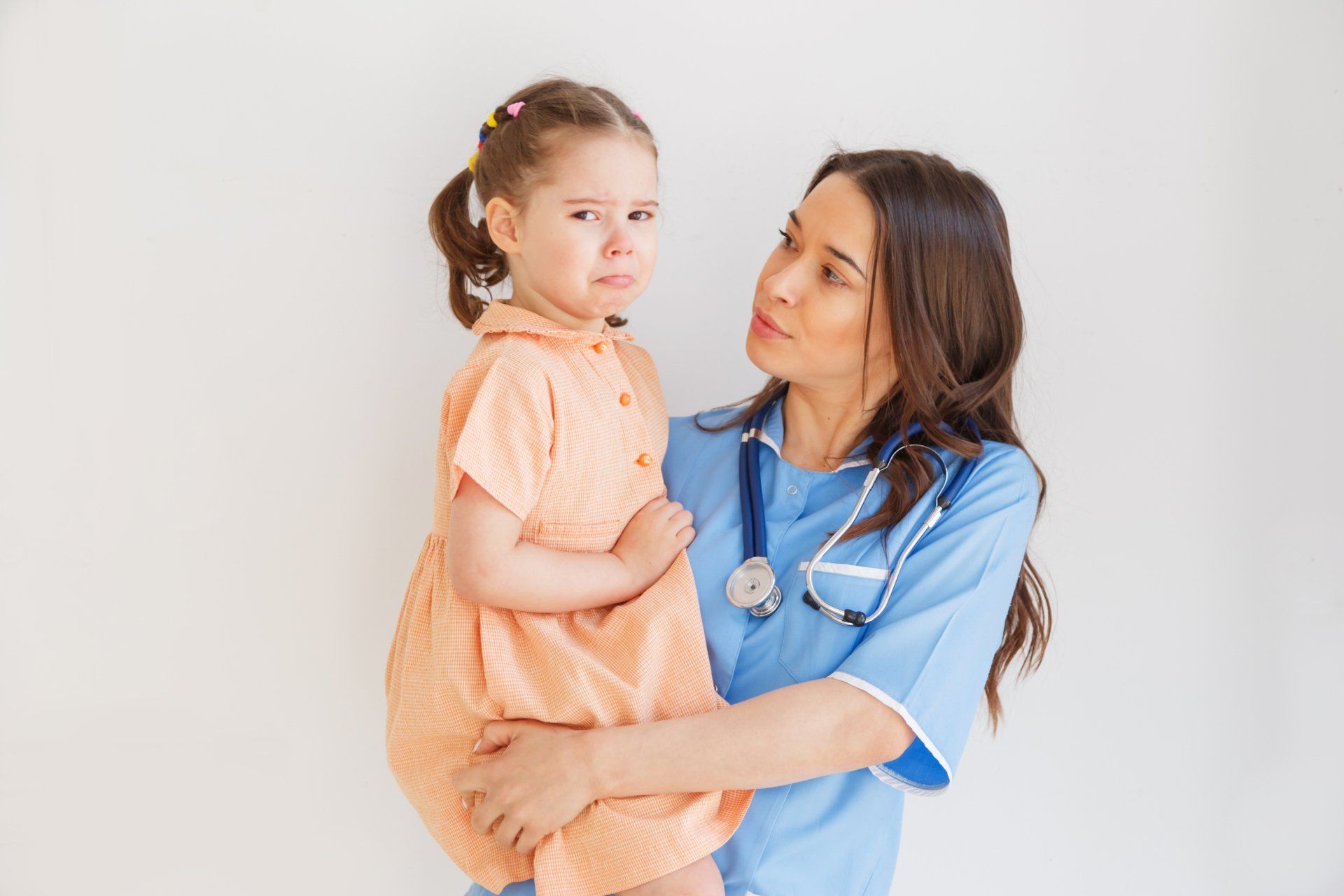 A nurse is holding a little girl in her arms.