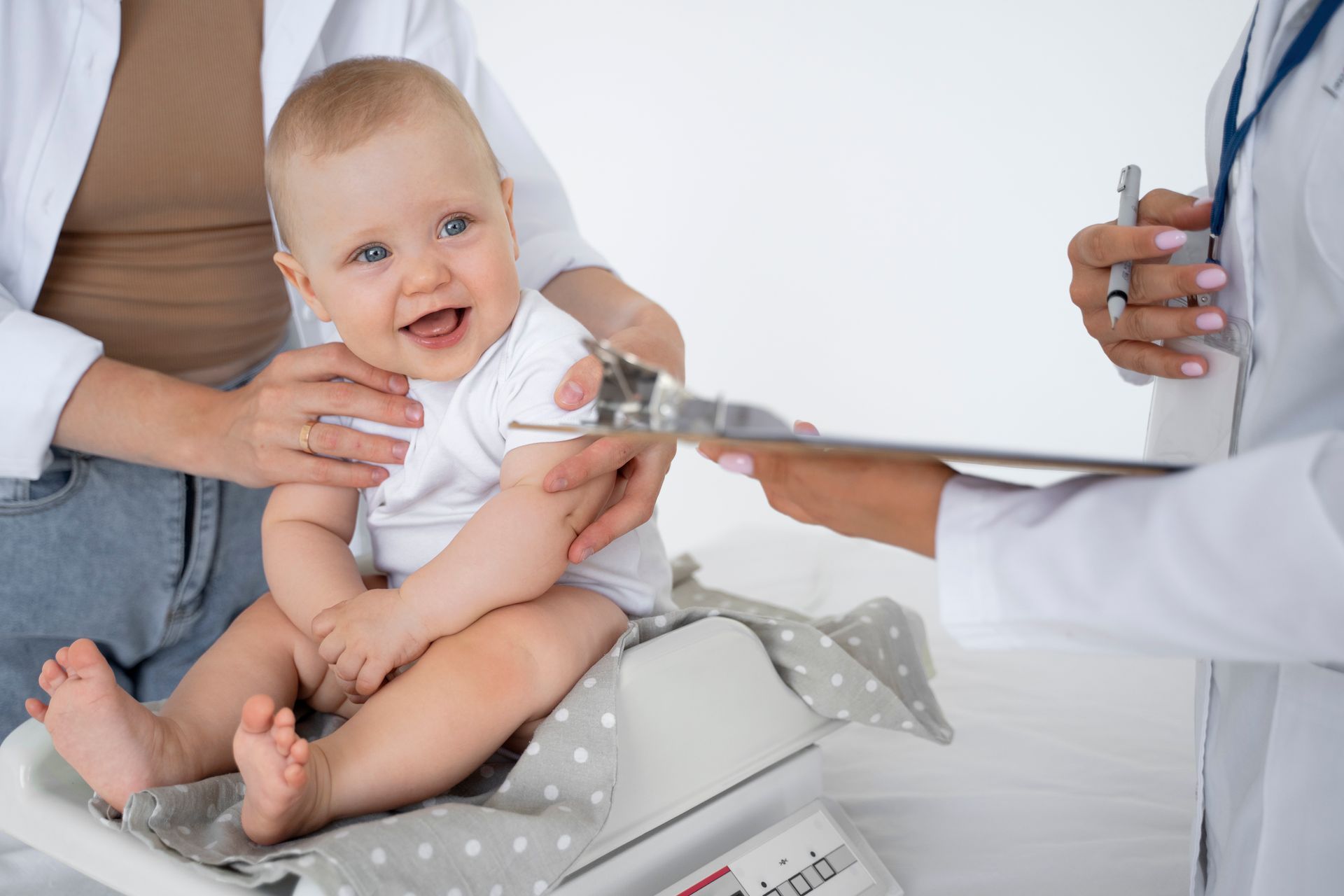 A baby is sitting on a scale while a doctor looks on.