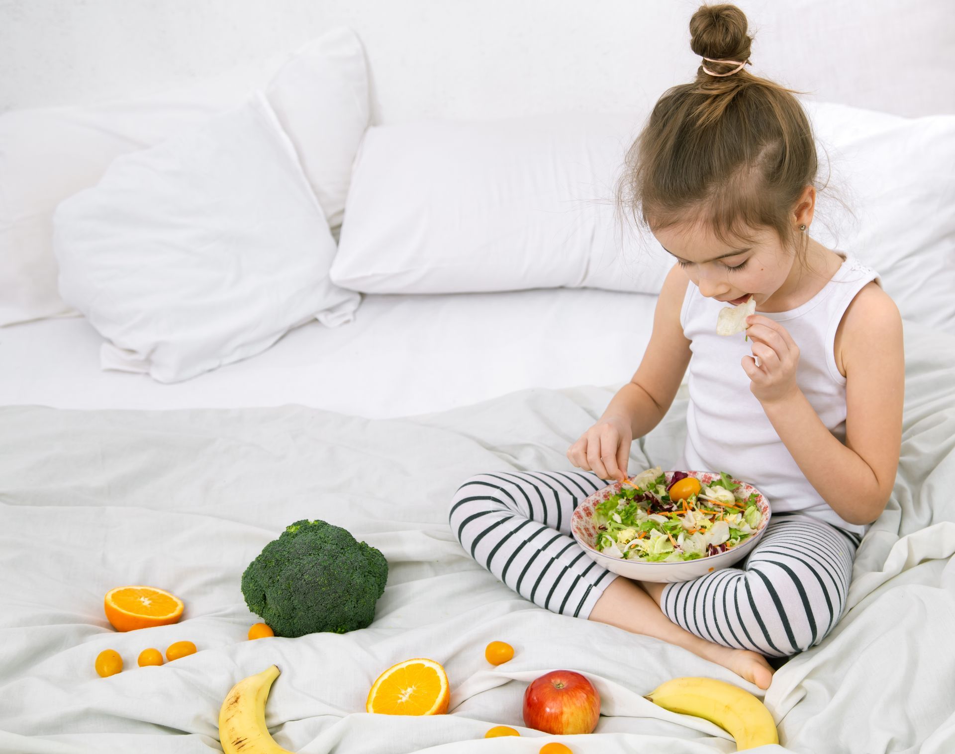 A child happily eating a salad, reducing overweight health risks through healthier eating habits.