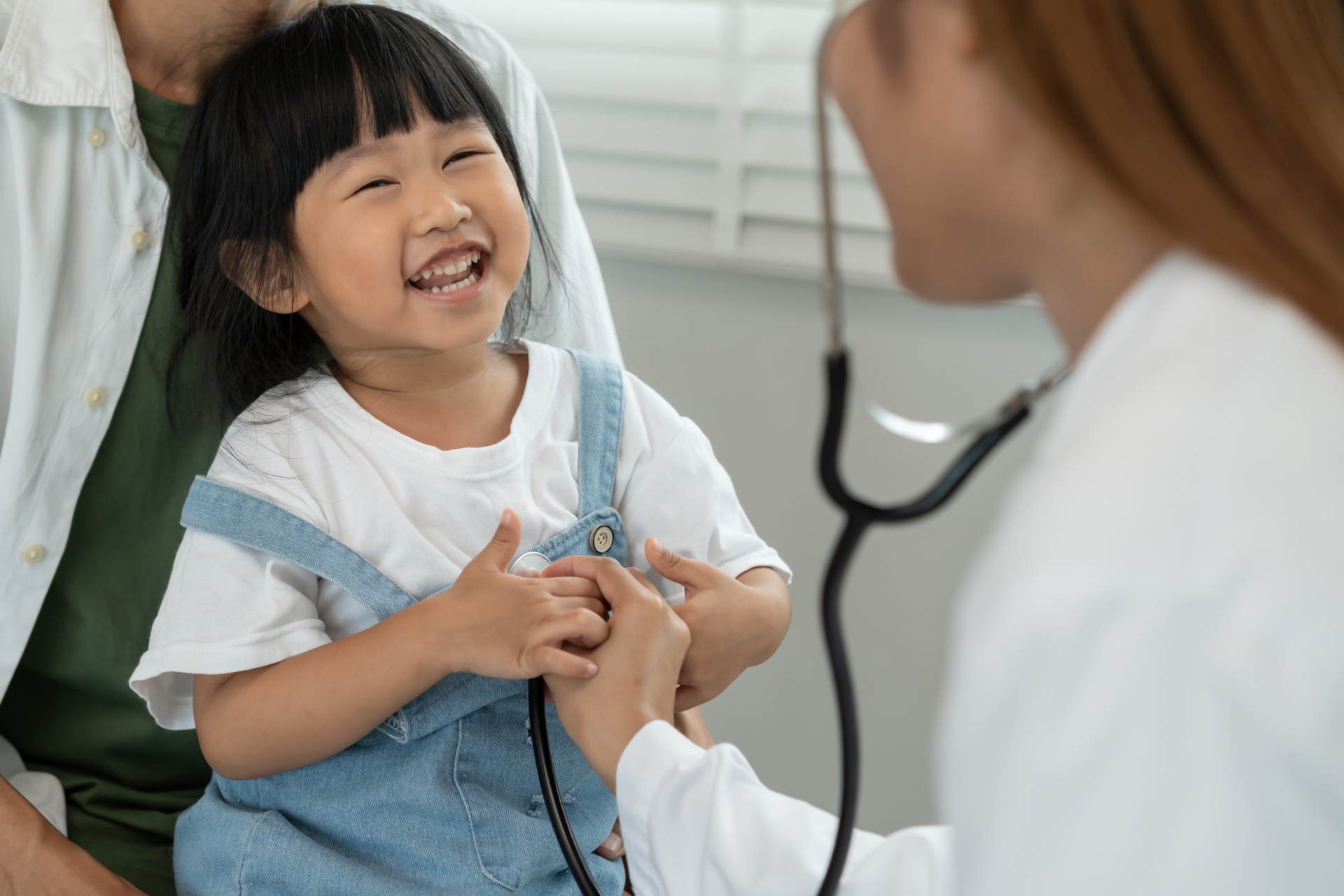 A smiling toddler laughing during a checkup, showing comfort and trust inside the pediatric office.