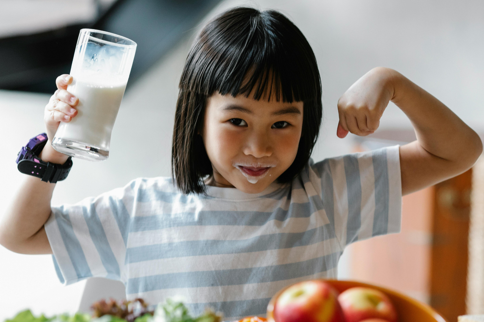 A smiling child enjoying a glass of milk as part of balanced childhood nutrition.