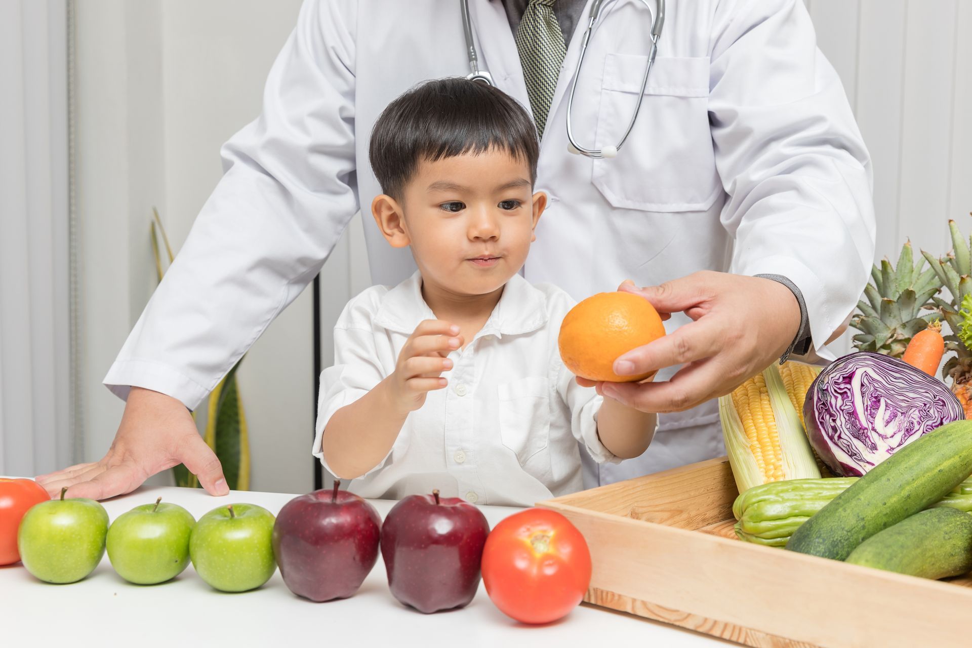 A doctor presents a variety of fruits and vegetables to a child, encouraging the children's healthy diet.