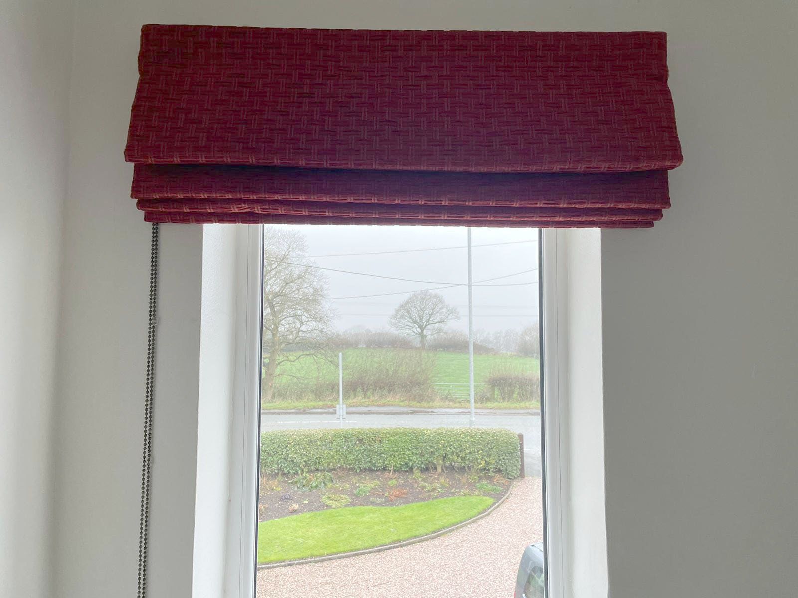 A window with a red roman blind on it.