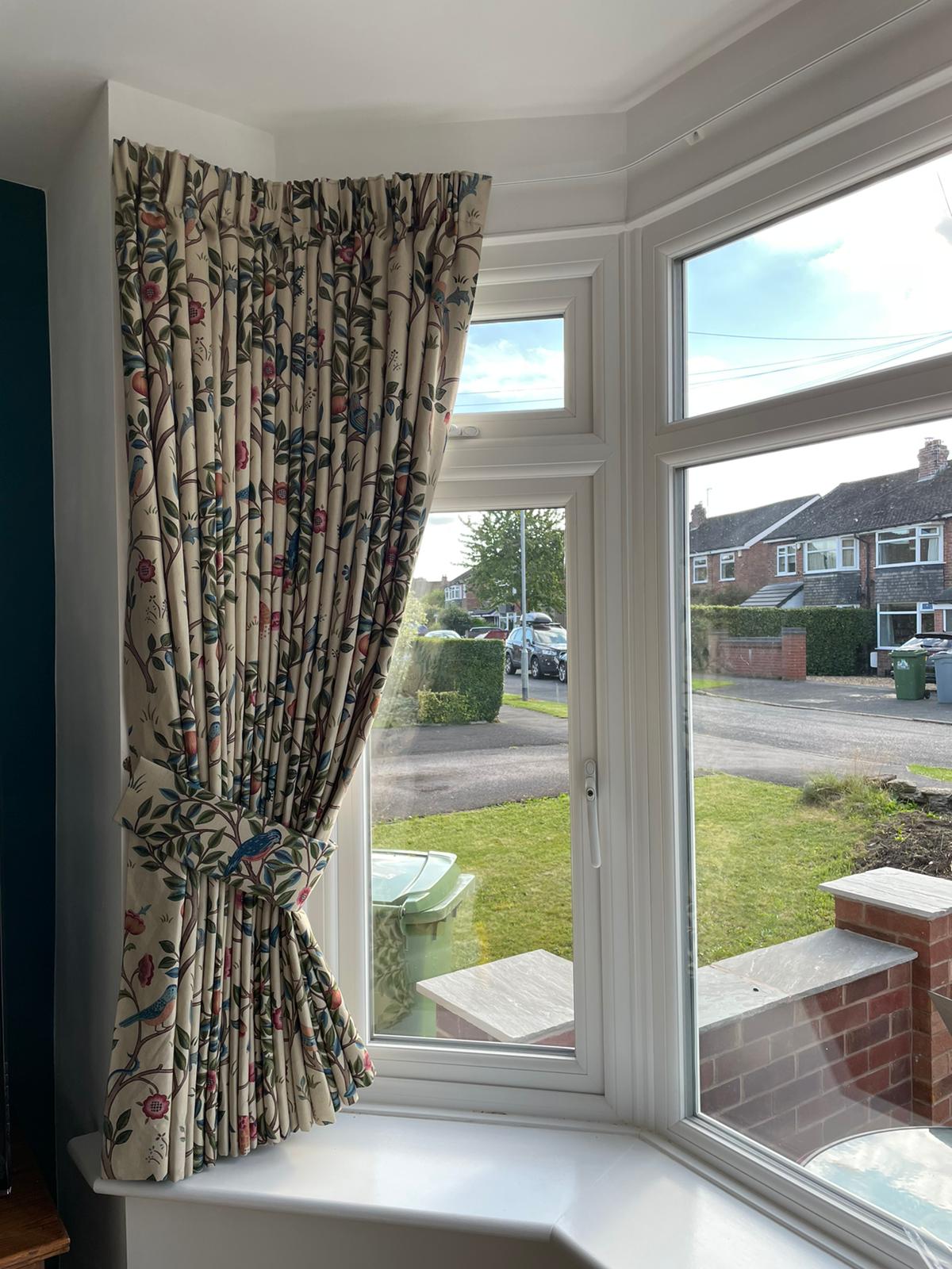 A window with curtains on it and a view of a street.