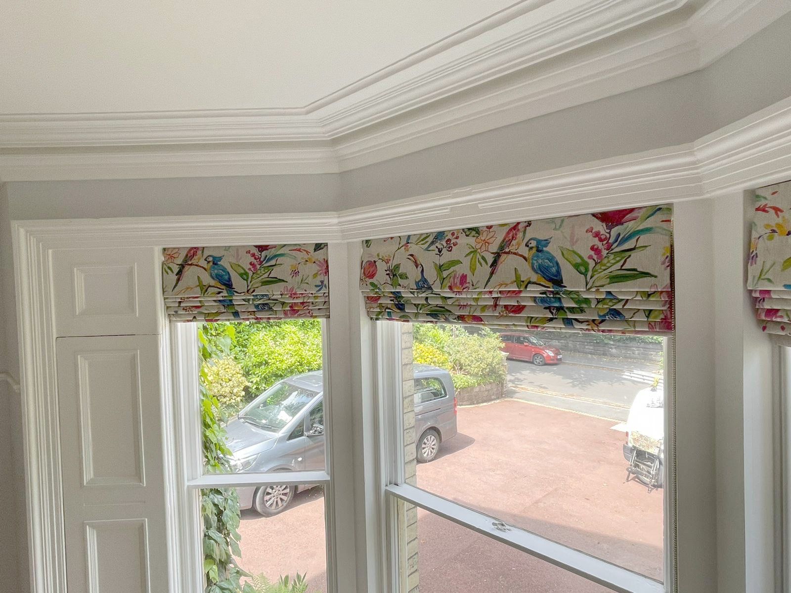 A room with two windows and a car parked in the driveway.