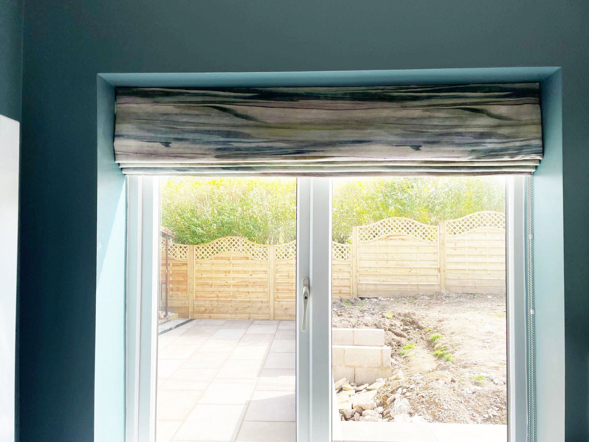 A window with a roman blind on it and a sliding glass door.