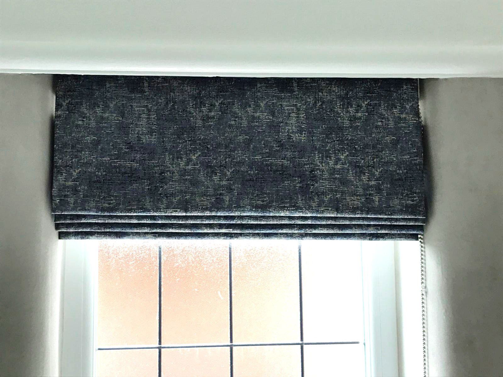 A close up of a window with a roman blind on it.