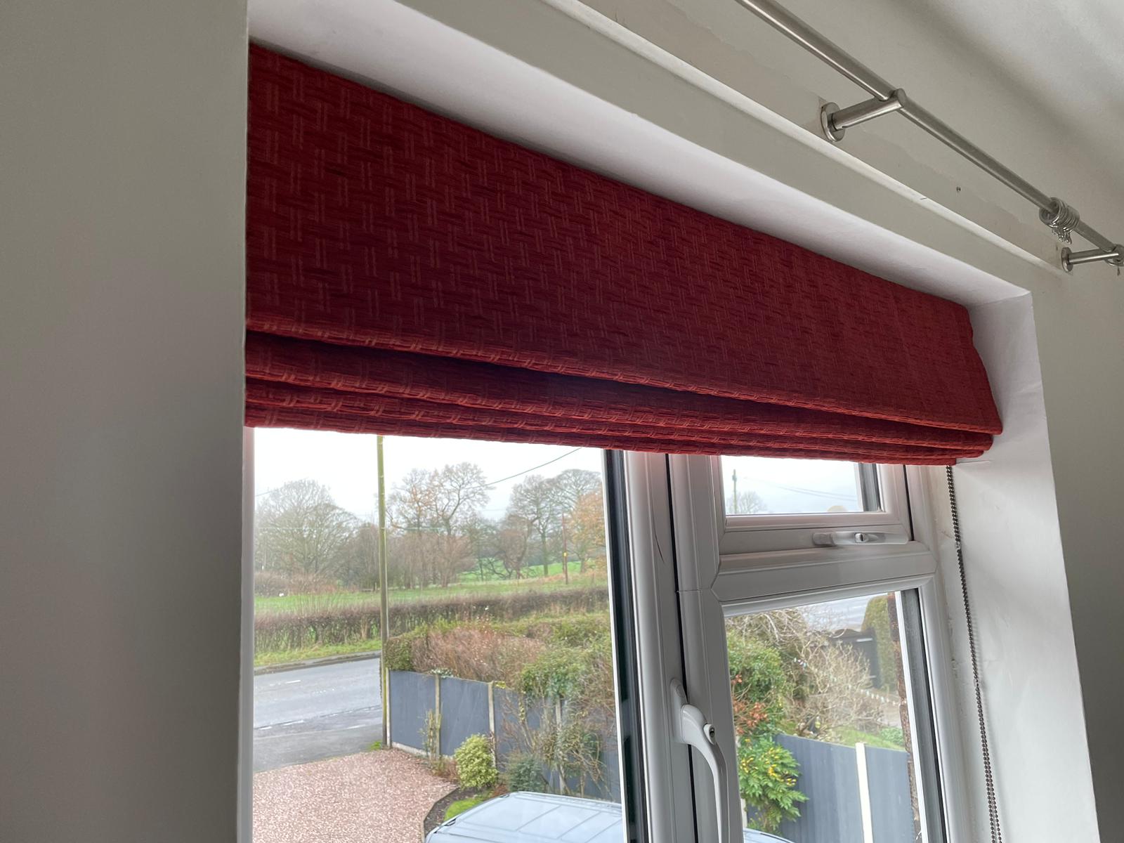 A window with a red roman blind on it.