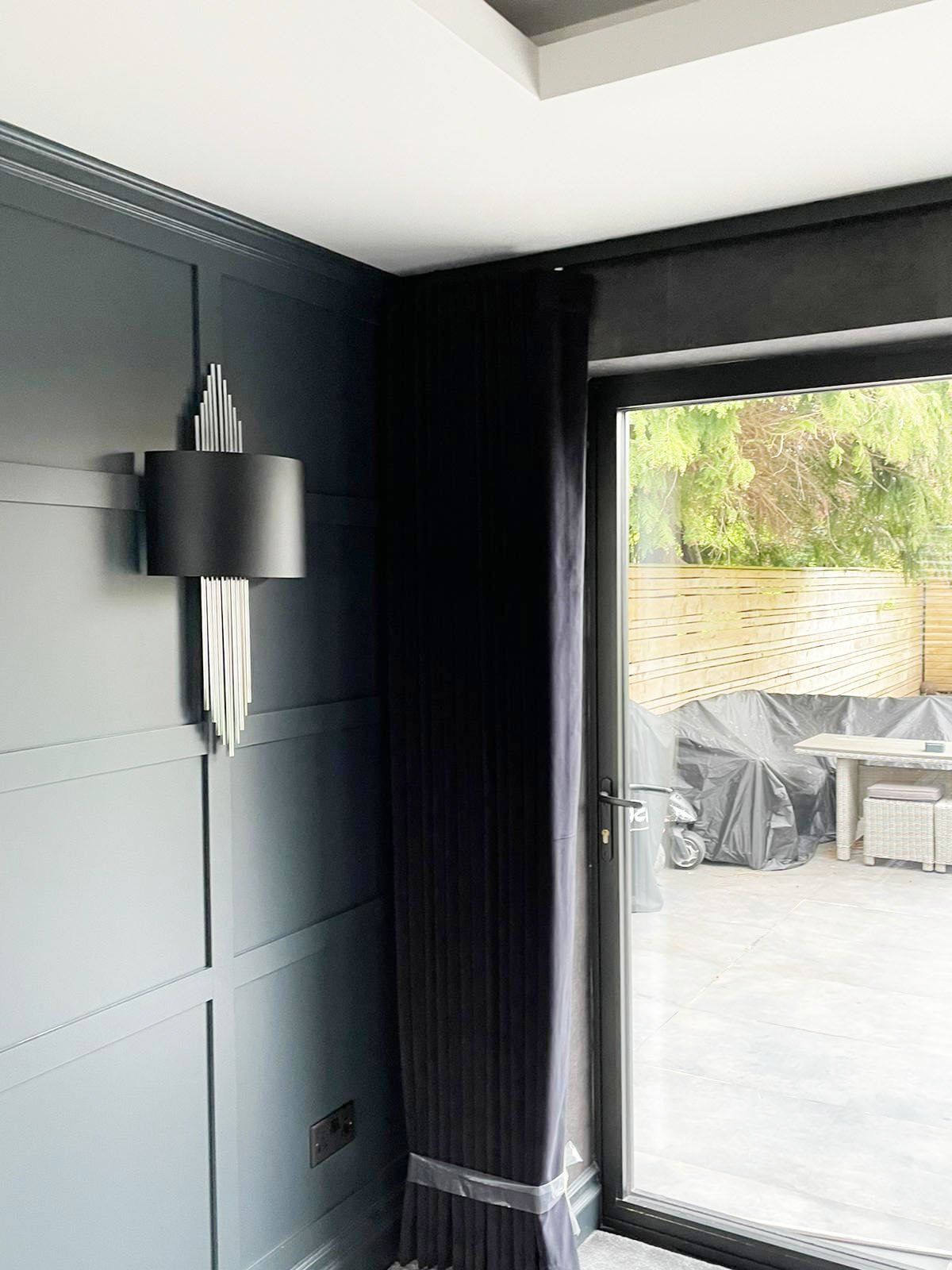 A room with a sliding glass door and a lamp on the wall.