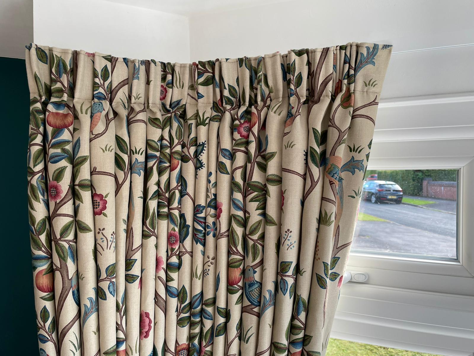 A pair of curtains with a floral pattern are hanging on a window.