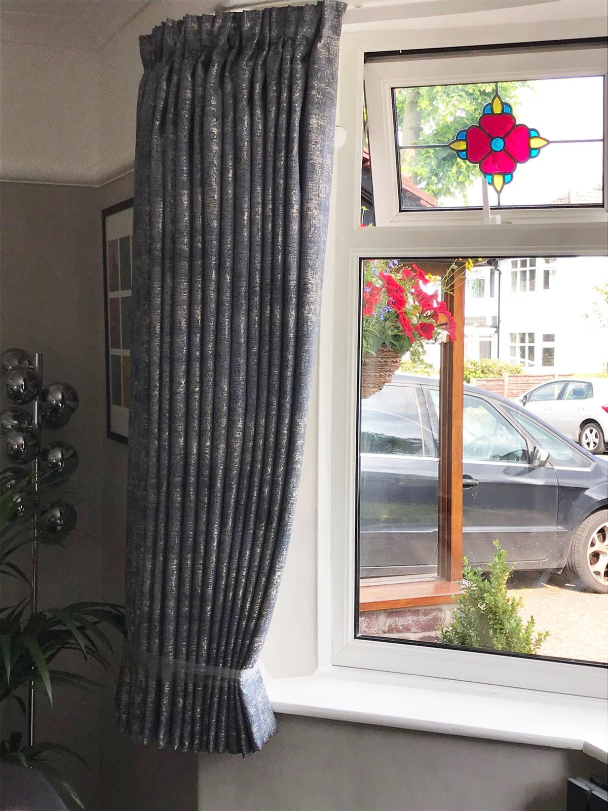A living room with a window with curtains and a stained glass window.
