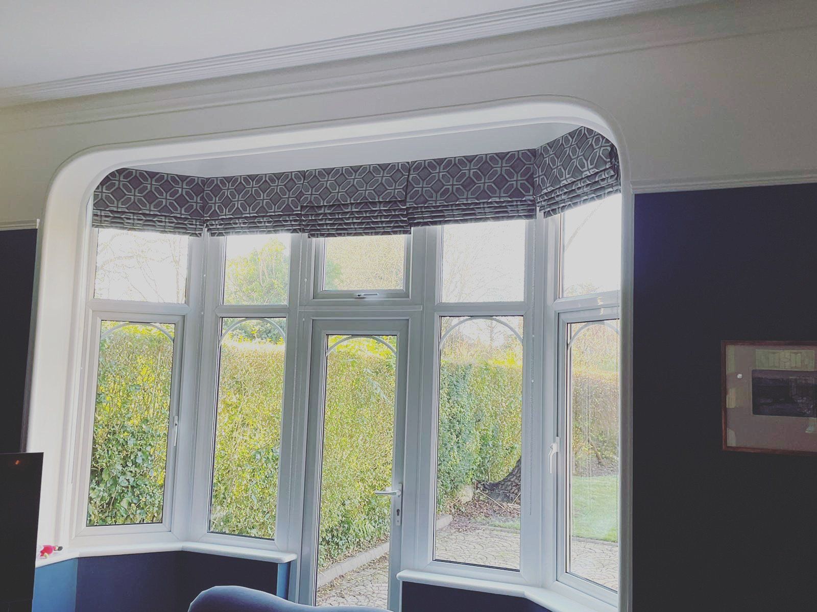 A living room with a large bay window and a couch.