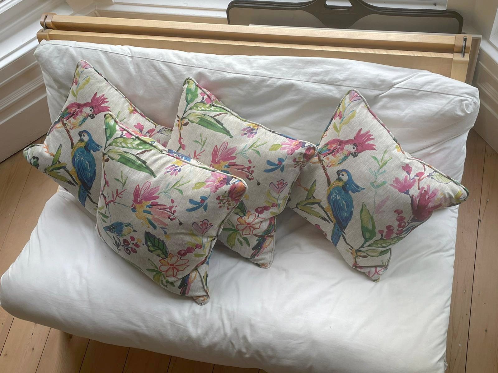 Three pillows with birds on them are sitting on a white couch