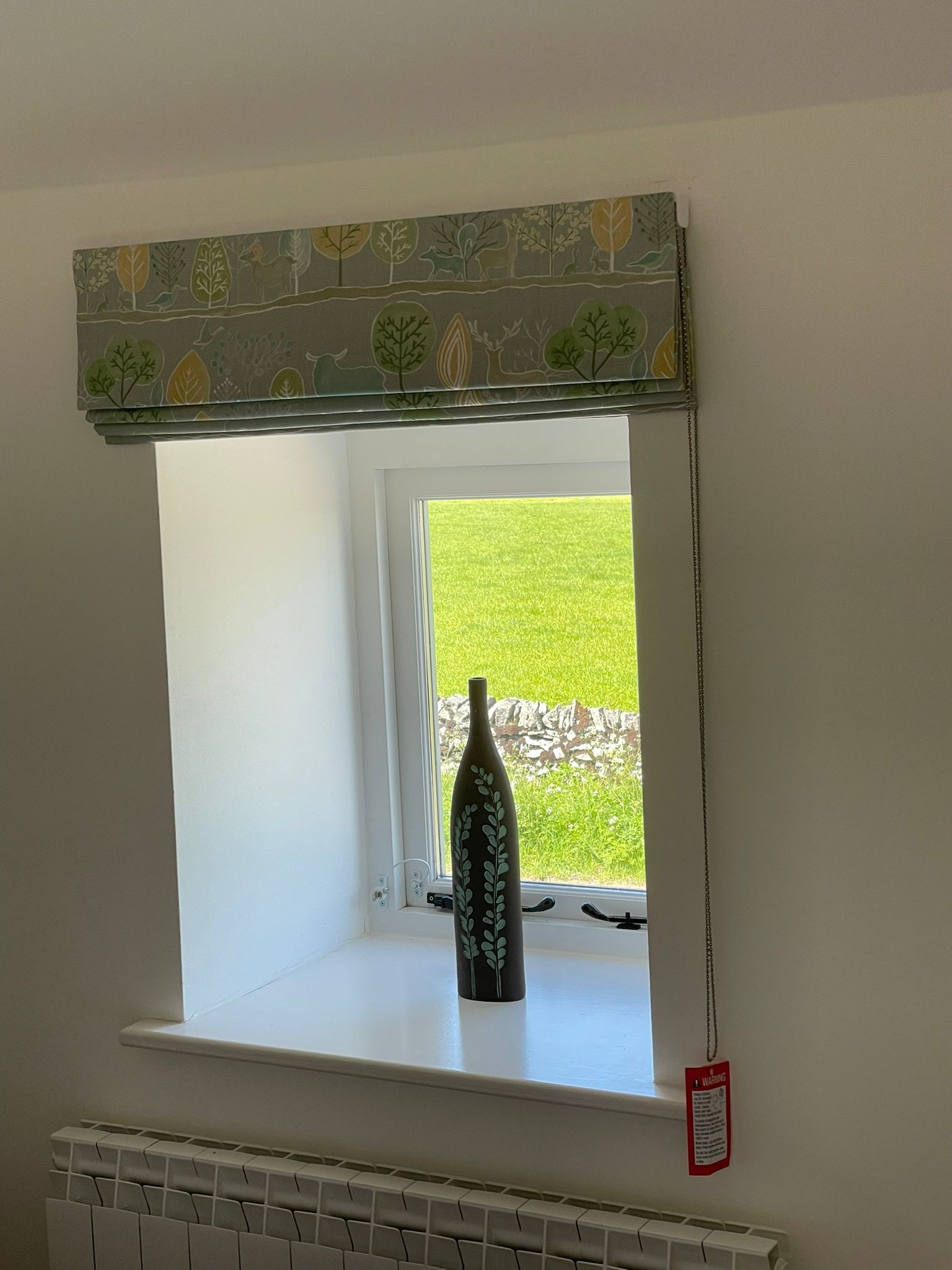 A bottle of wine is sitting on a window sill next to a window.