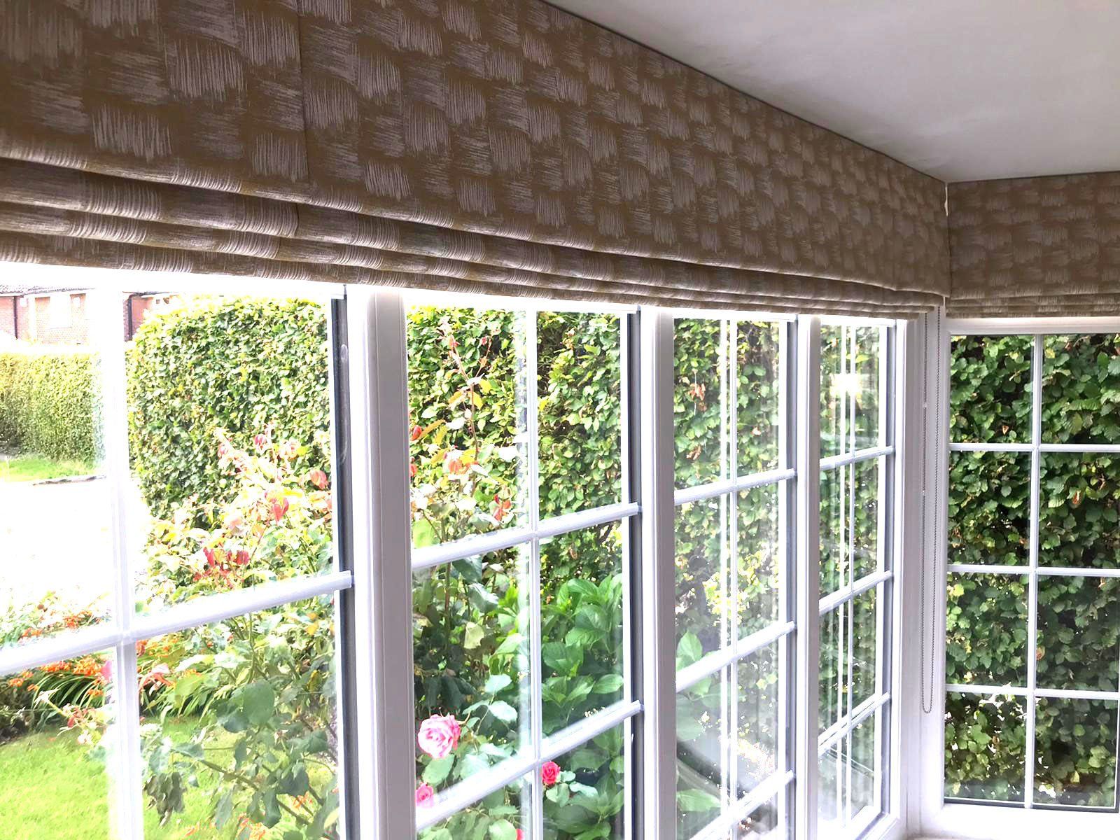 A room with a lot of windows and a garden in the background.