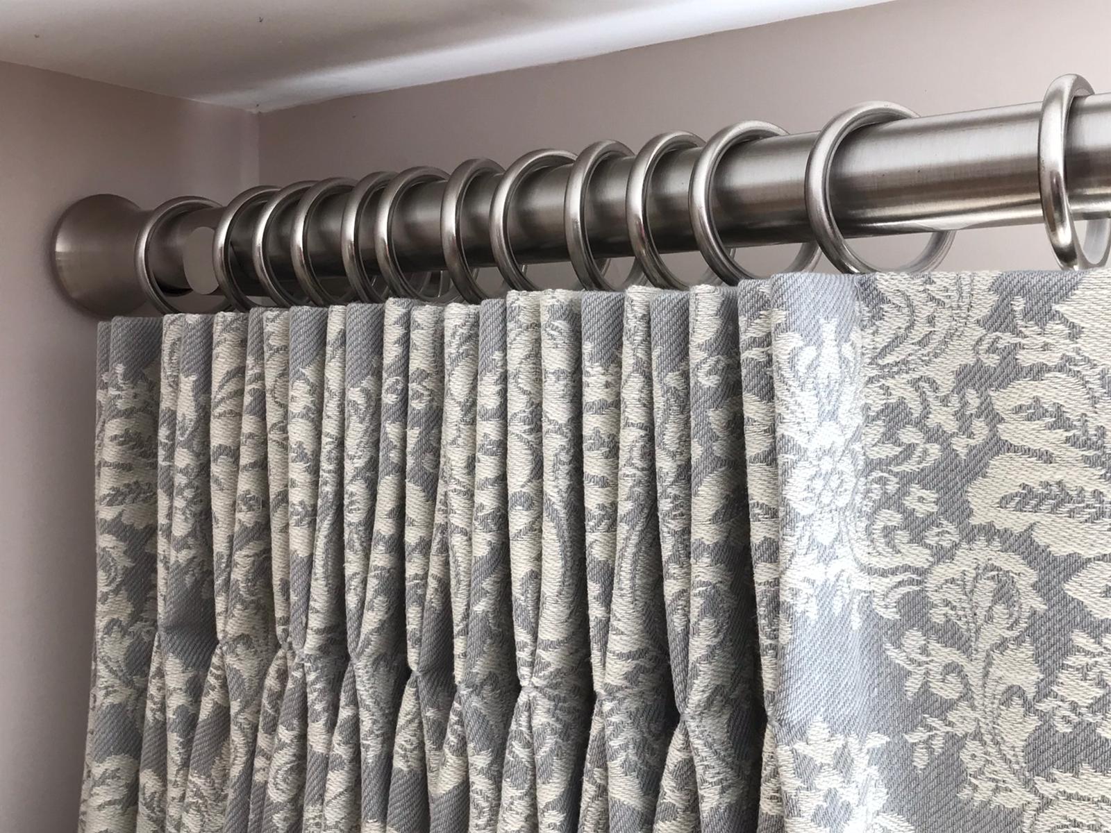 A close up of a pair of curtains hanging on a curtain rod.