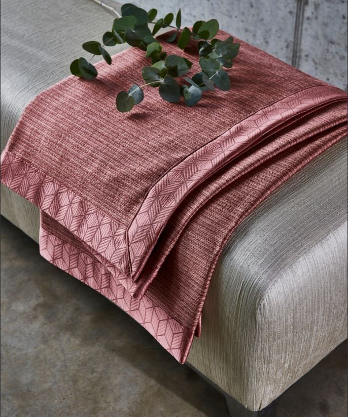 A pink blanket is sitting on top of a bed