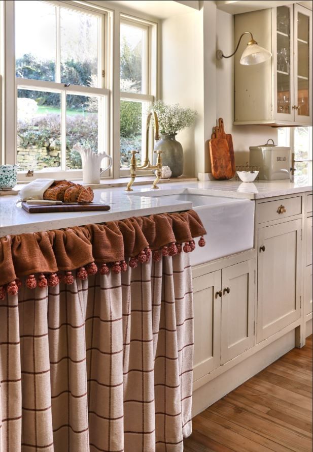 A kitchen with a sink and curtains on the counter