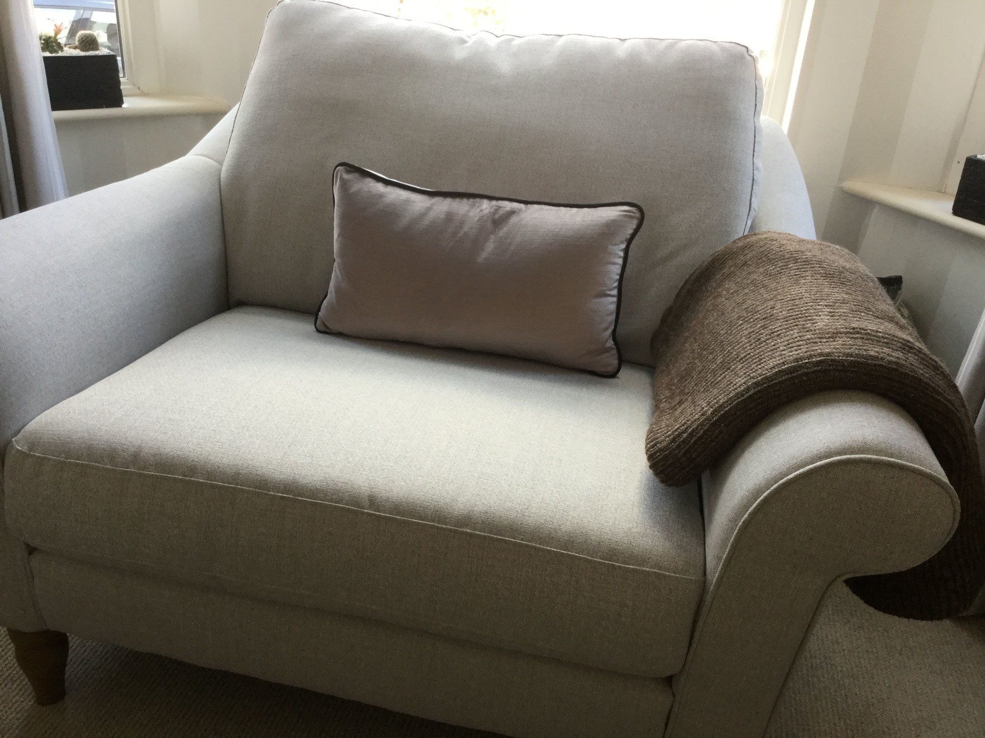 A chair with a pillow and a blanket on it in a living room.