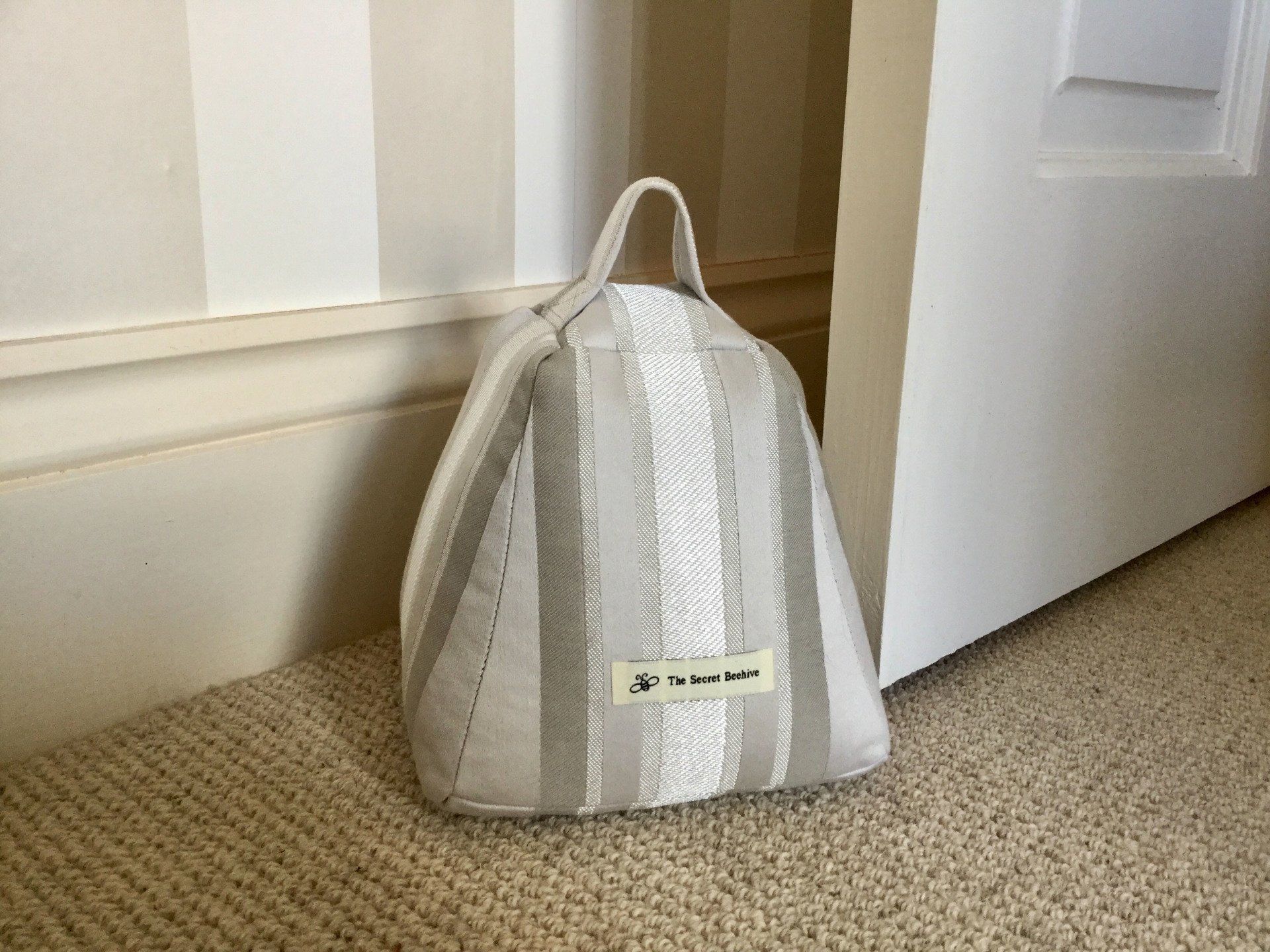A striped door stop is sitting on the floor next to a door.