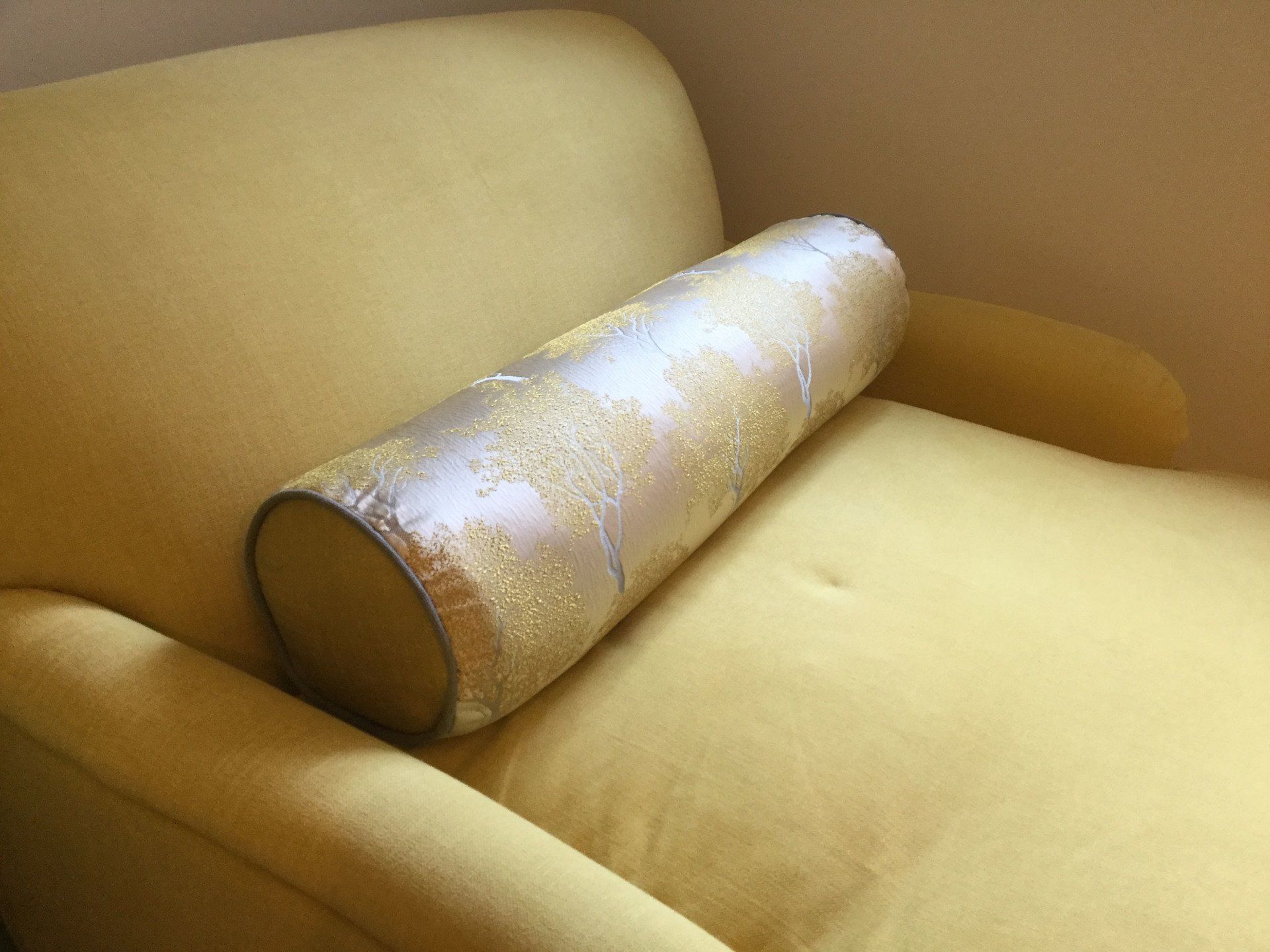 A yellow chair with a pillow on the arm rest