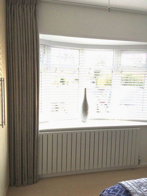 A bedroom with a large window and a radiator.