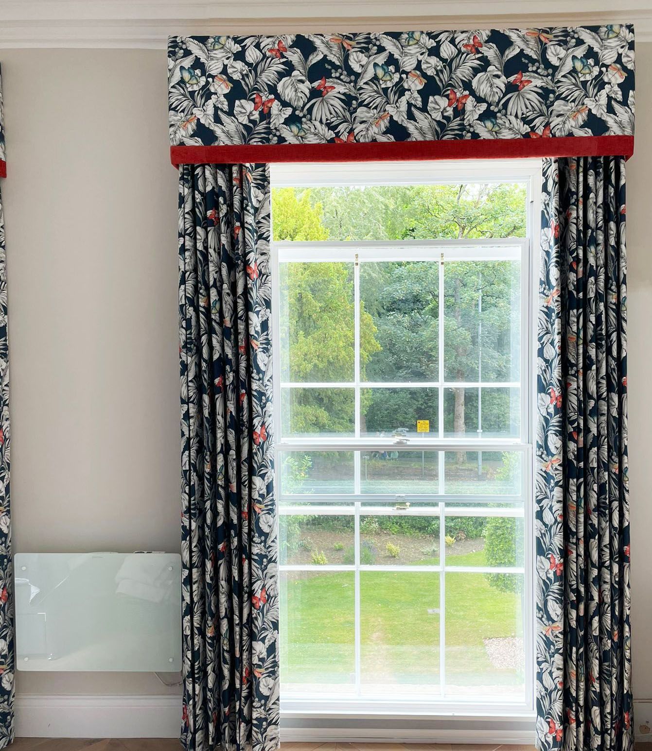 A window with floral curtains and a red trim