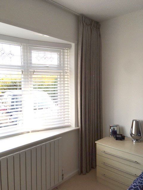 A bedroom with a dresser and a window with blinds