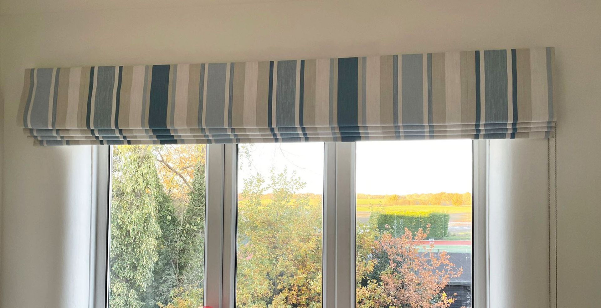 A window with a striped curtain hanging over it.