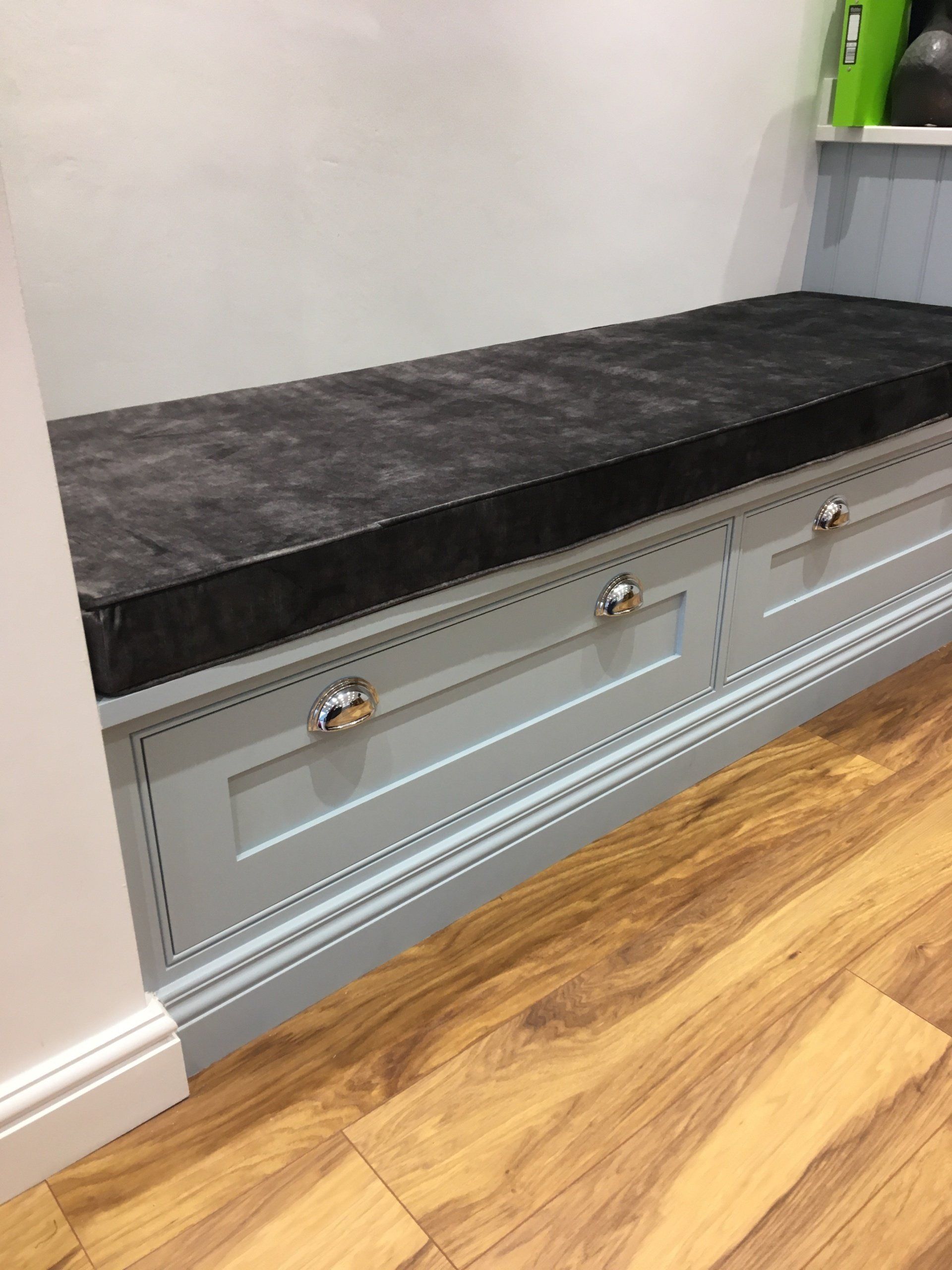 A bench with drawers underneath it and a black cushion.