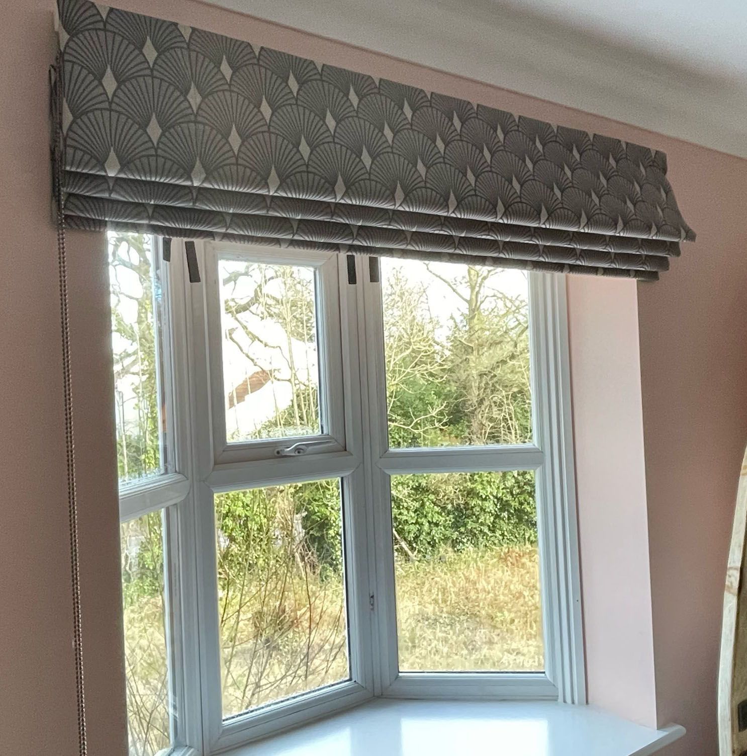 A window with a gray roman shade on it